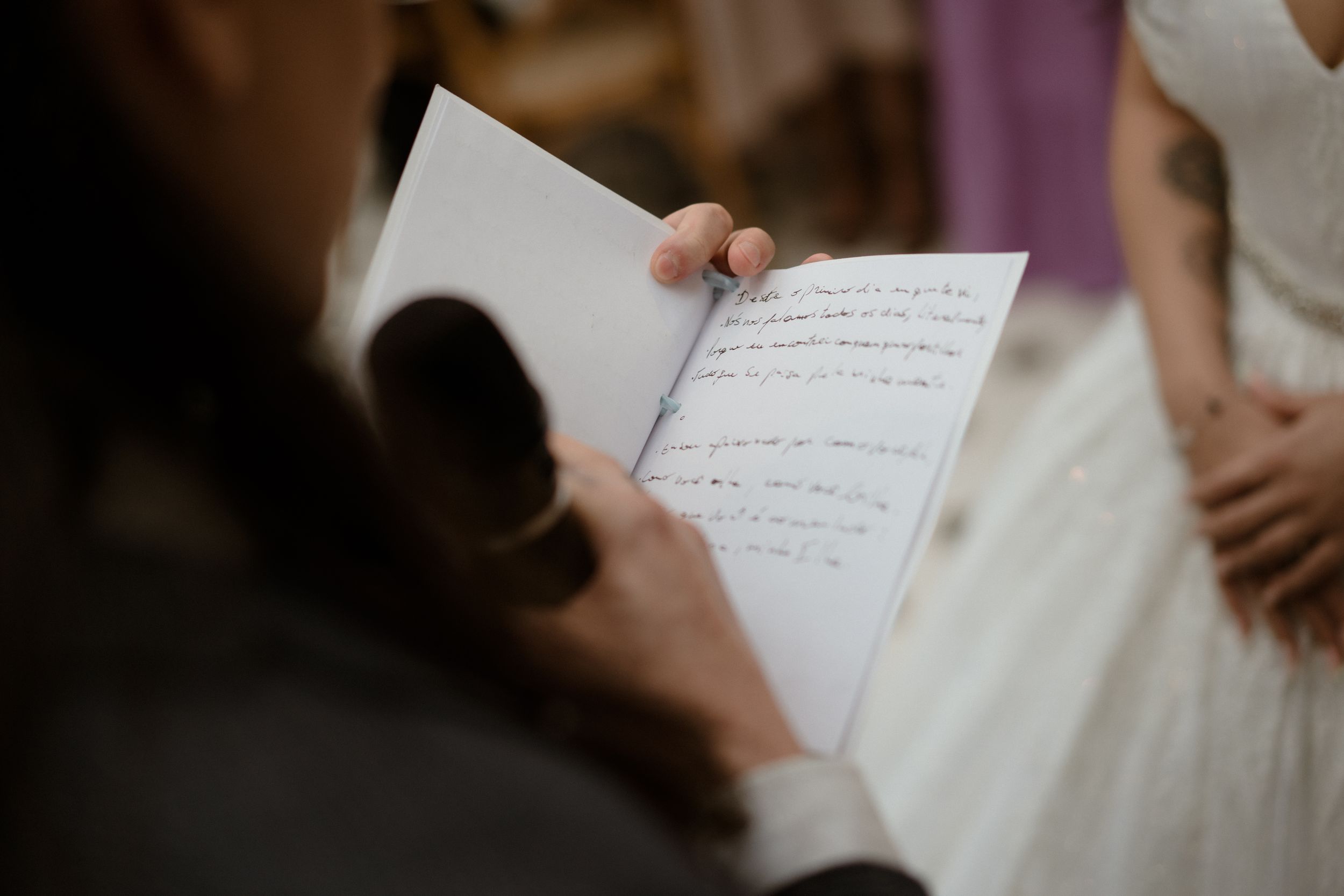 Wedding couple exchanging vows while holding handwritten notes.