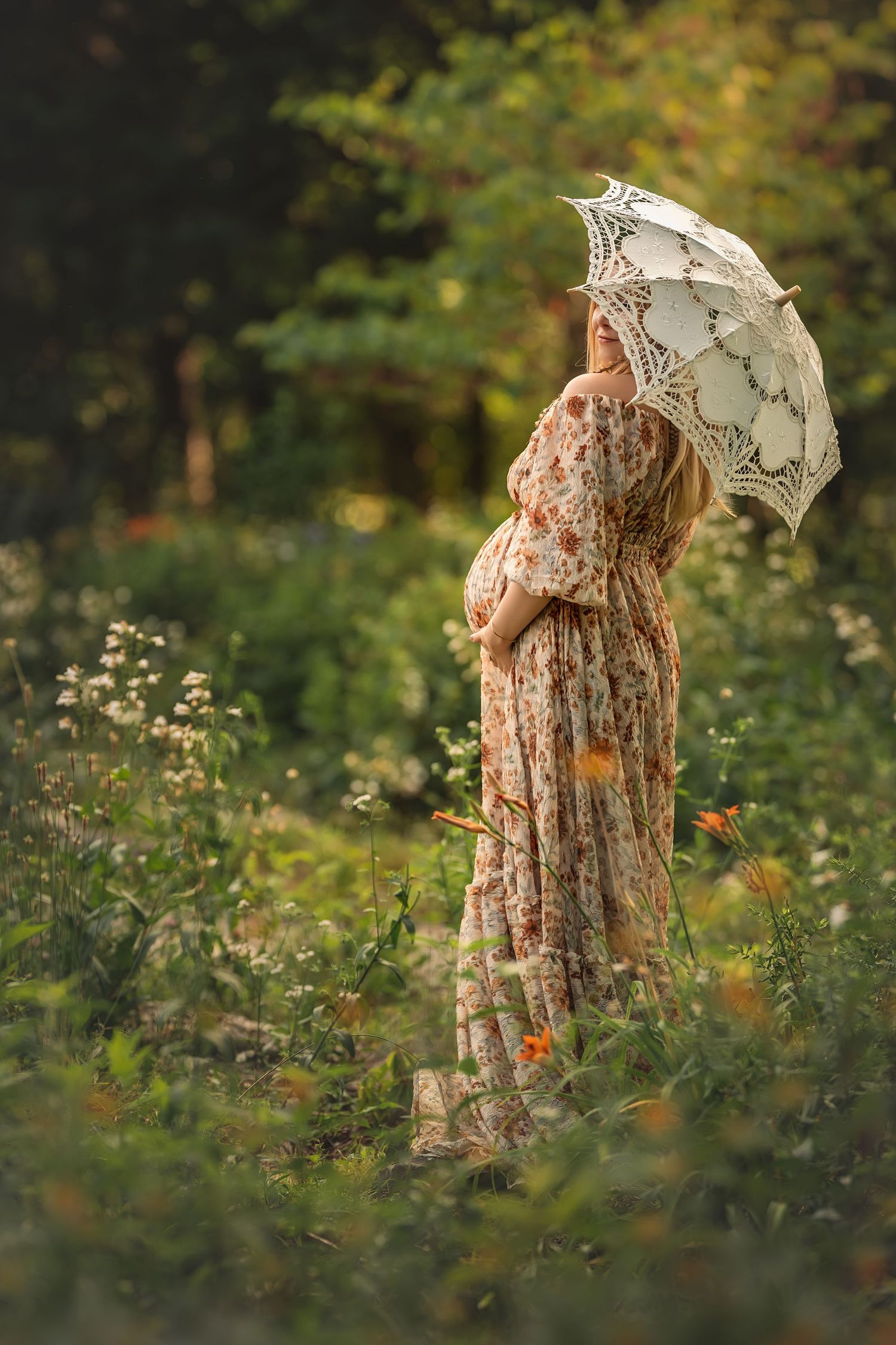 A dreamy outdoor maternity photo with a vintage dress and lace parasol in a wildflower meadow at golden hour.
