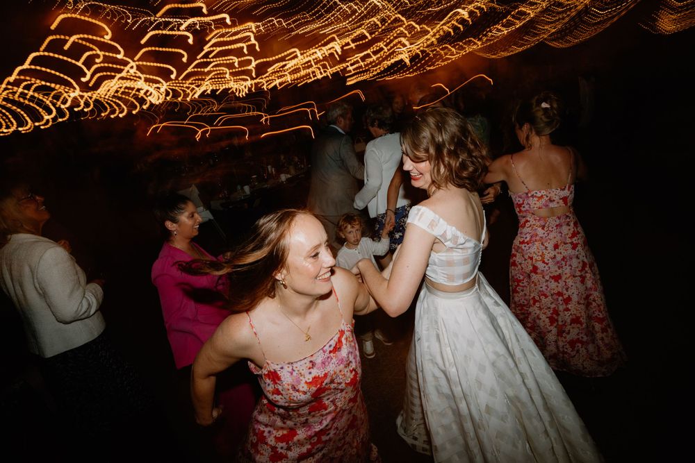 Wedding celebration captured with motion blur under warm overhead string lights.