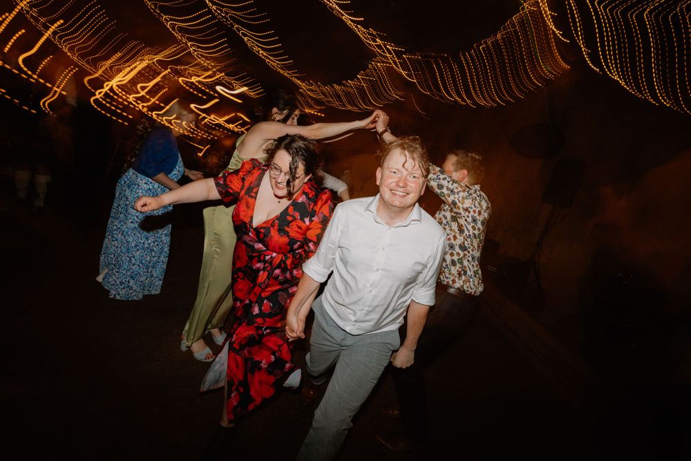 Lively group dancing together at a wedding reception under warm lighting.