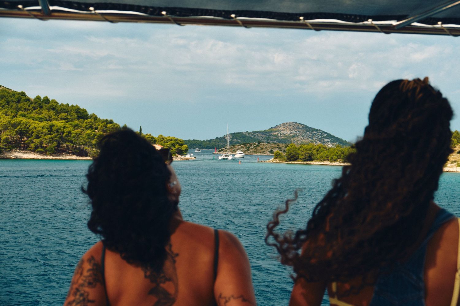 Rear view of passengers enjoying scenic views from a boat deck in Mediterranean waters.