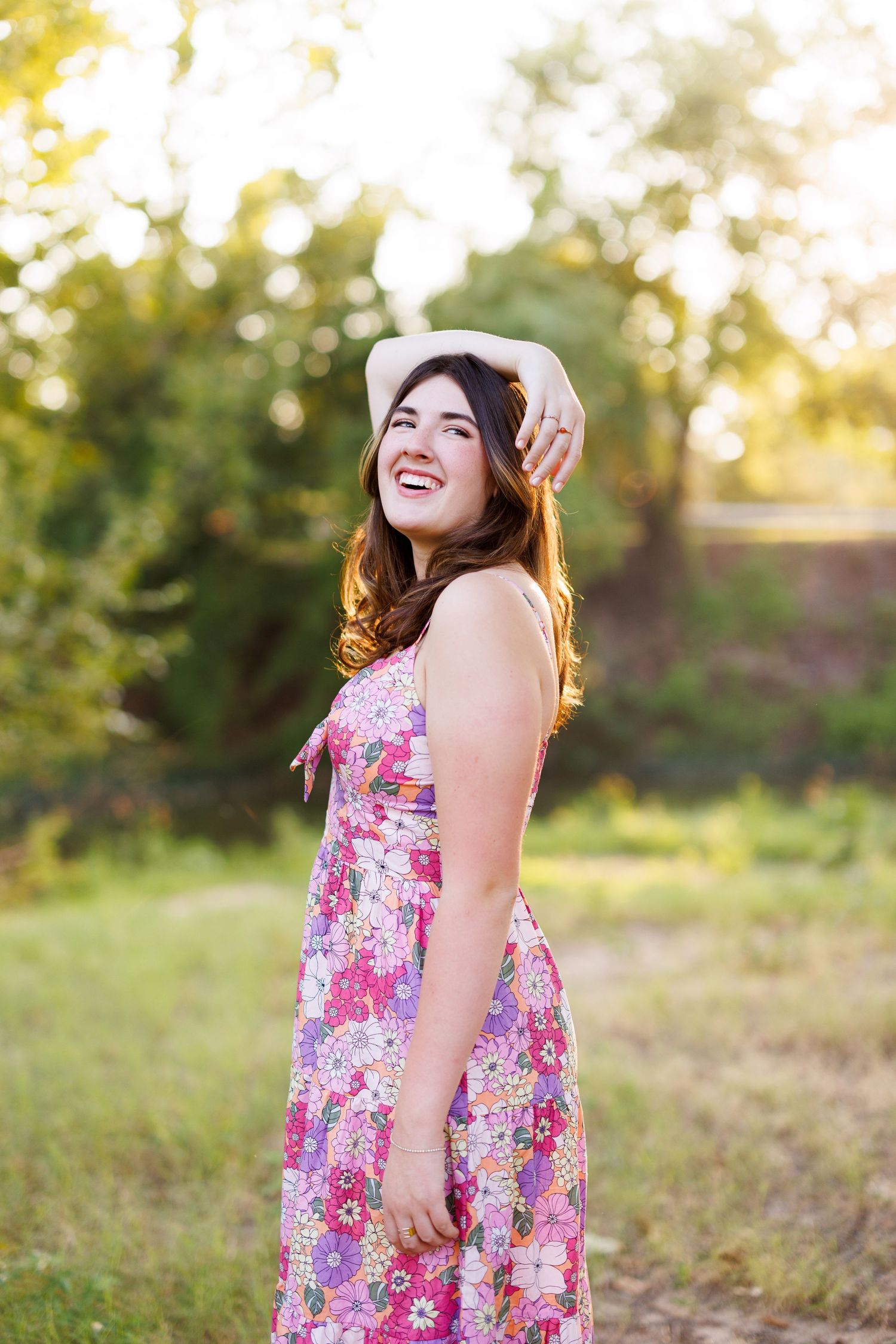 A floral sundress flows in golden sunlight during an outdoor summer photoshoot.