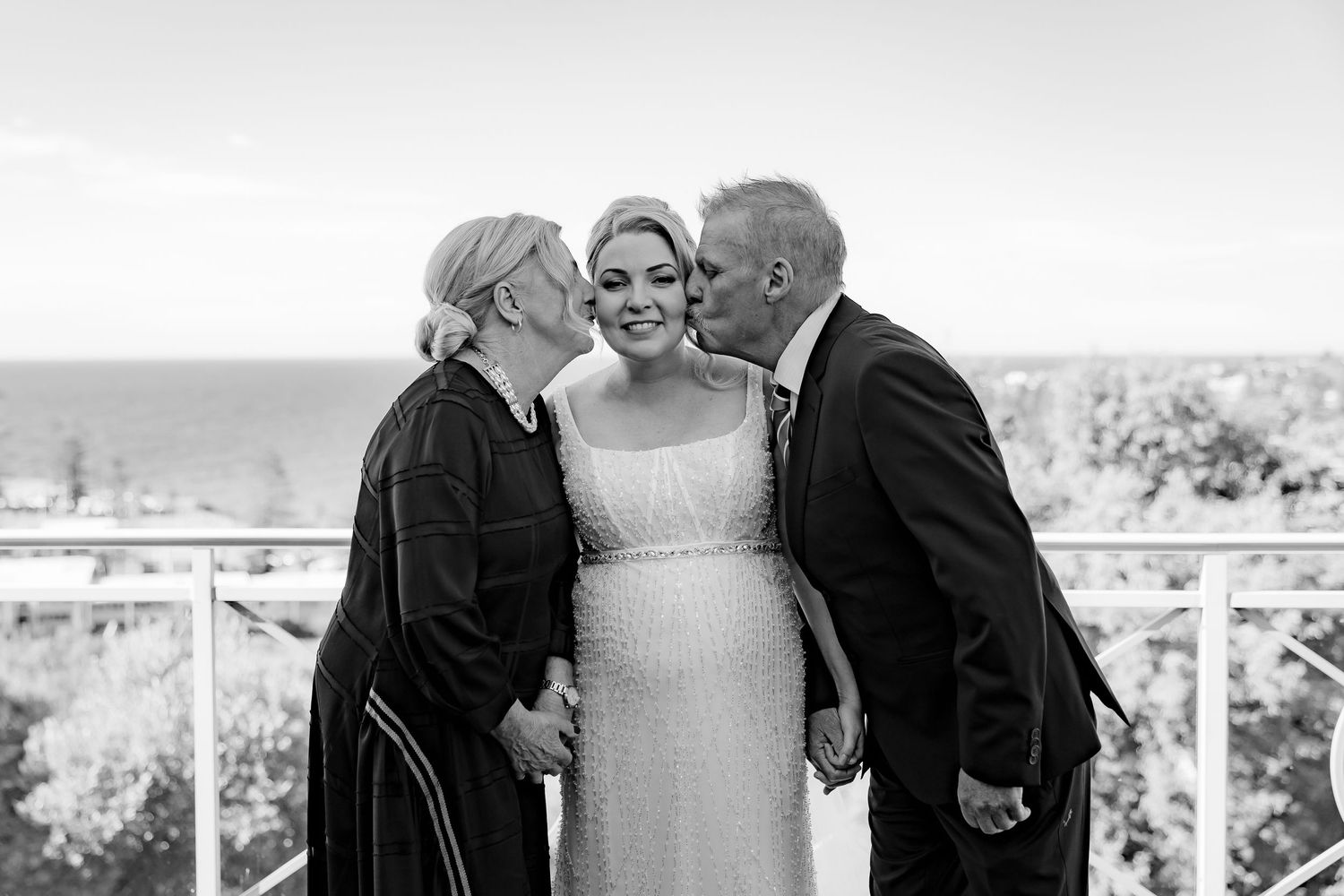 An intimate black and white moment captured on a balcony overlooking the ocean.