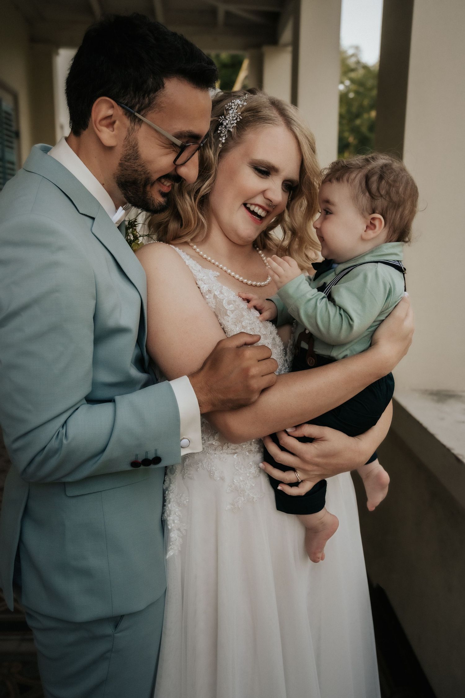 Wedding couple and child sharing joyful moment together outdoors.