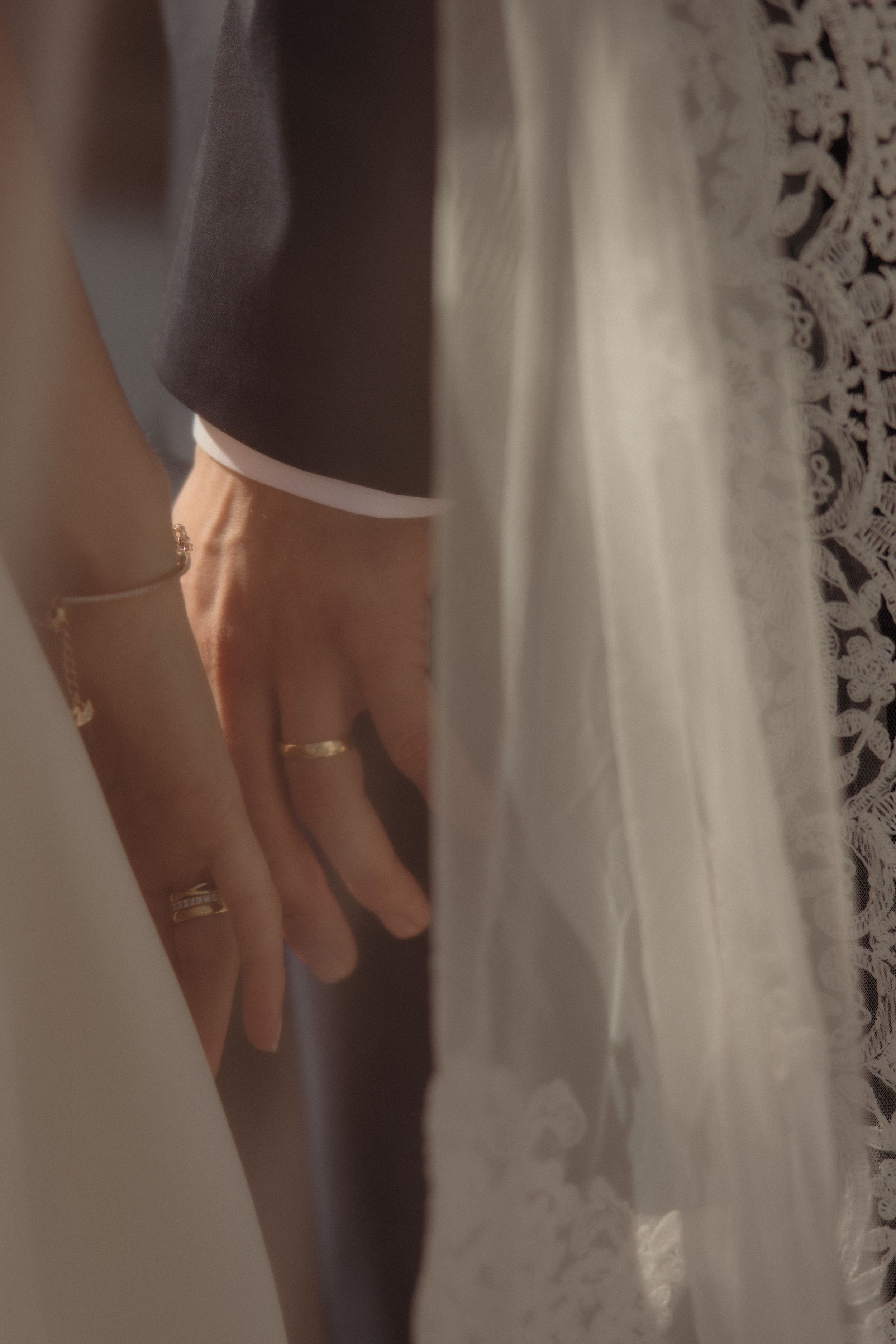 Close-up view of delicate lace details on a white wedding dress with hands gently touching the fabric.