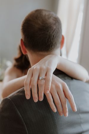 Close-up shots of hands with wedding rings against a grey suit in romantic engagement or wedding photography.