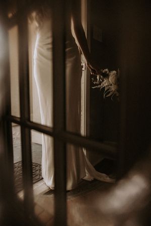 Light streams through window blinds creating dramatic shadows and patterns in a dark moody interior space.