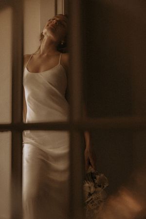 Artistic sequence of a bride in a white dress posing in moody indoor lighting.