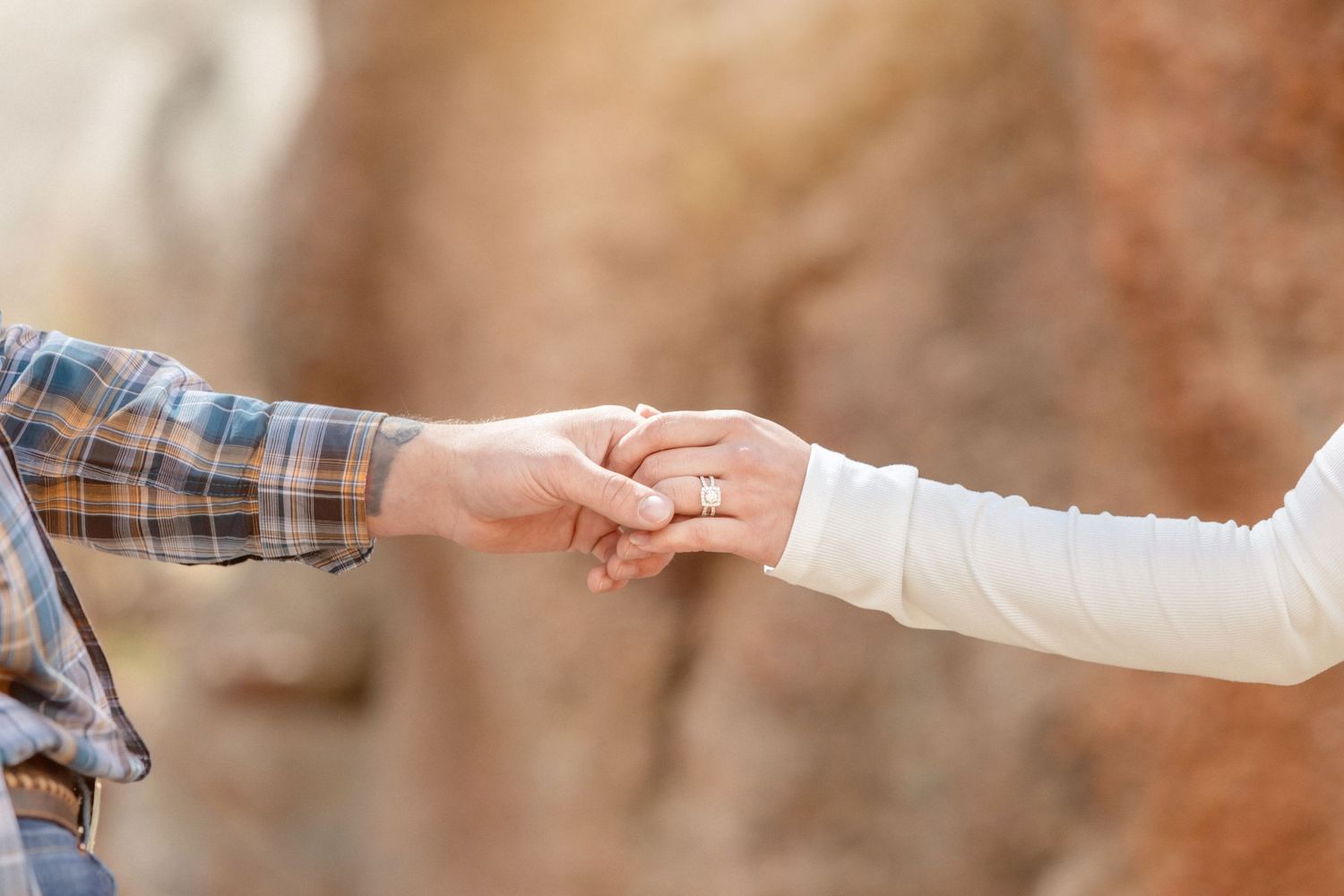 Close-up of hands reaching toward each other in an engagement or wedding moment.