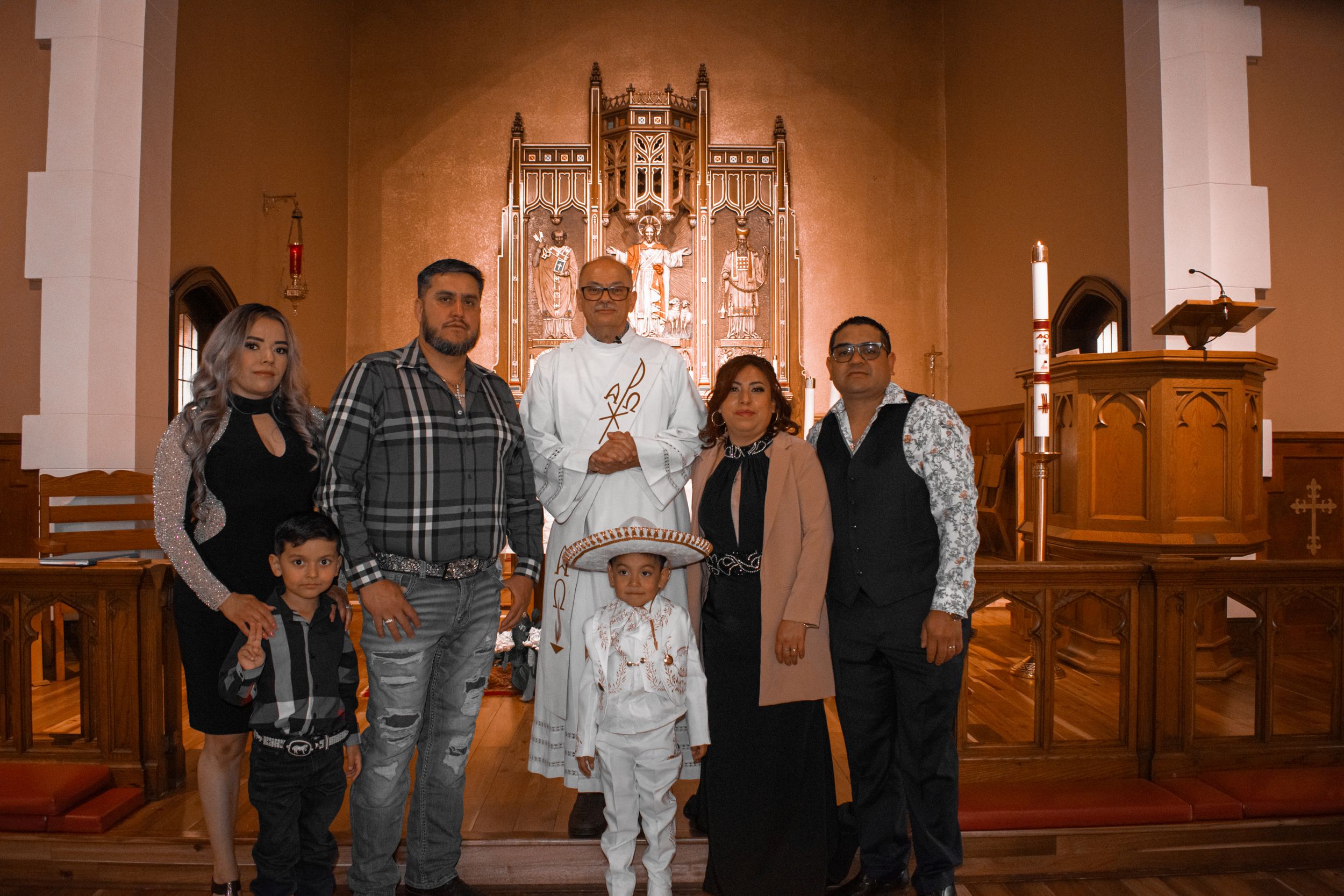 Group photo of a baptism celebration with an ornate church altar in the background.