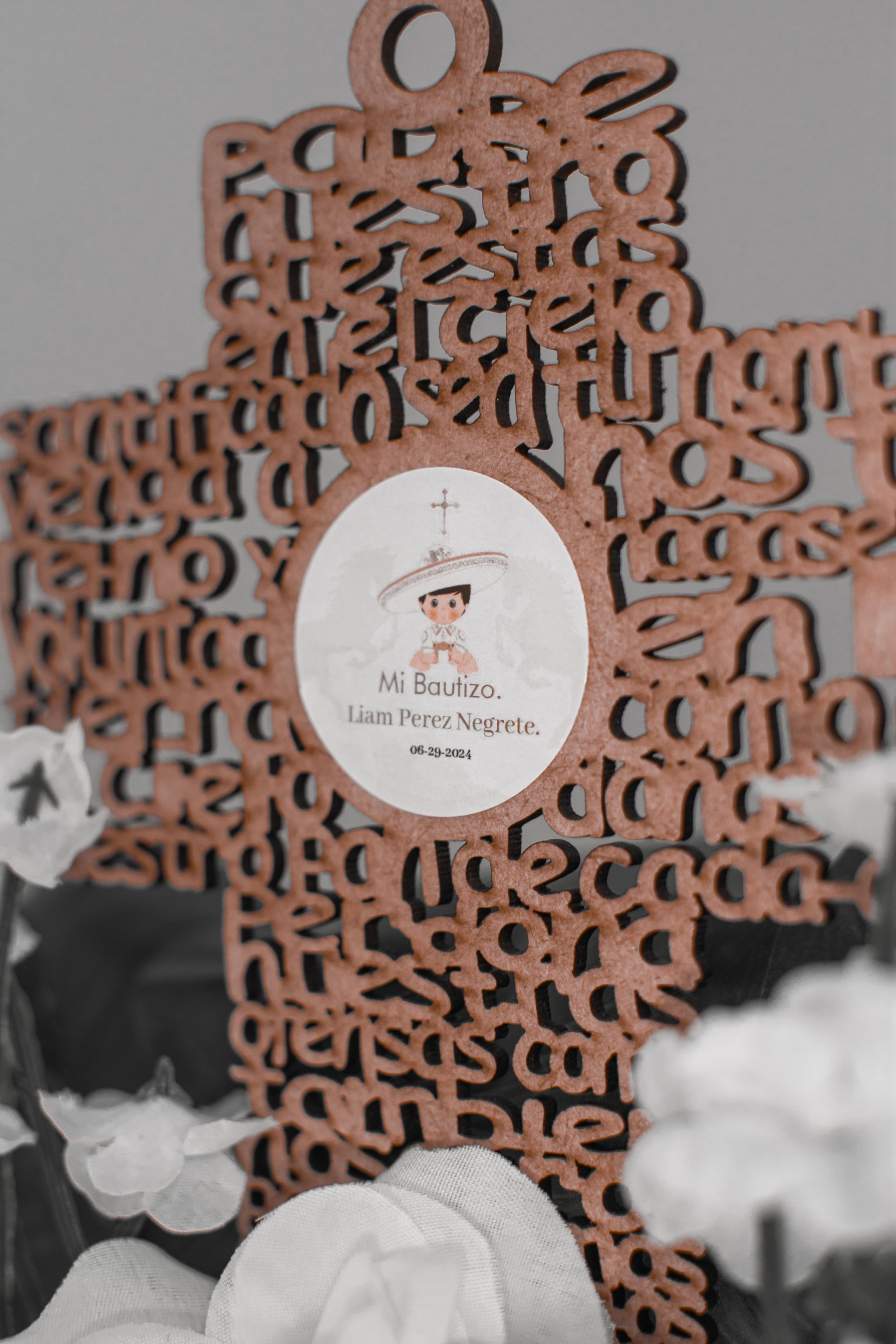Decorative wooden cross with baptism commemorative details in selective color photography.