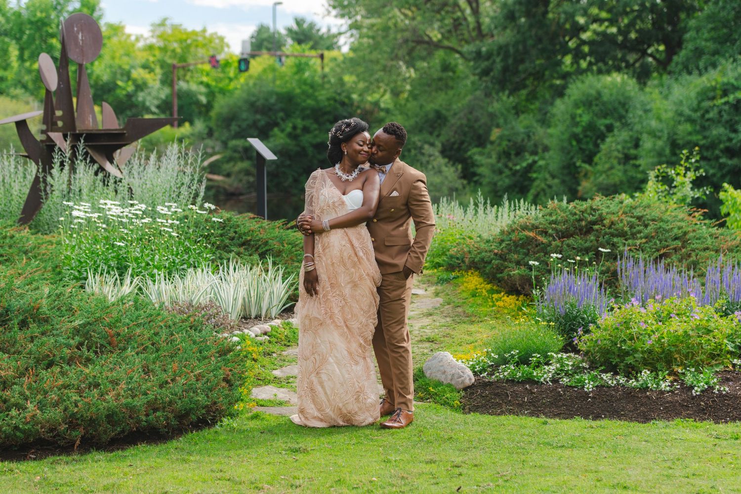 A romantic couple embraces in a lush garden filled with blooming flowers and greenery on their wedding day.