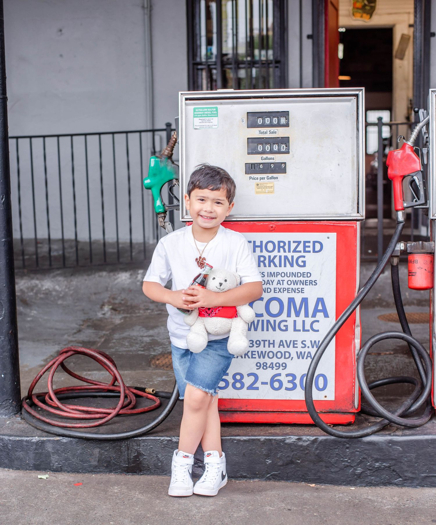 Person in white t-shirt standing near vintage gas pumps at a service station.