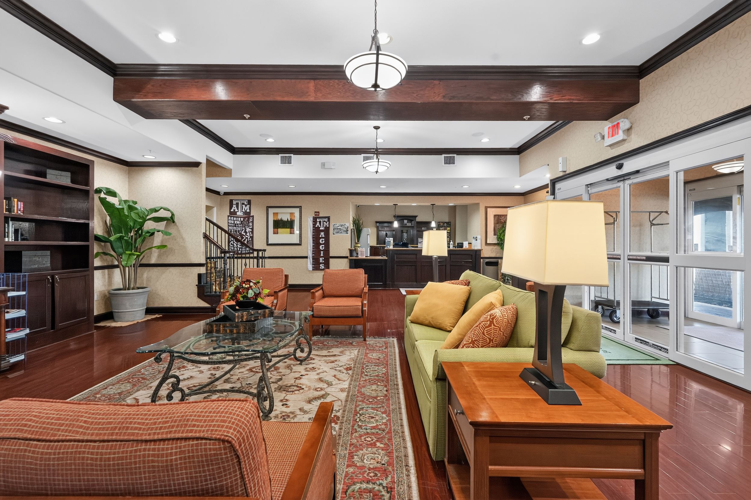Spacious hotel lobby with hardwood floors, coffered ceiling, plush seating, warm lighting, and elegant decor.