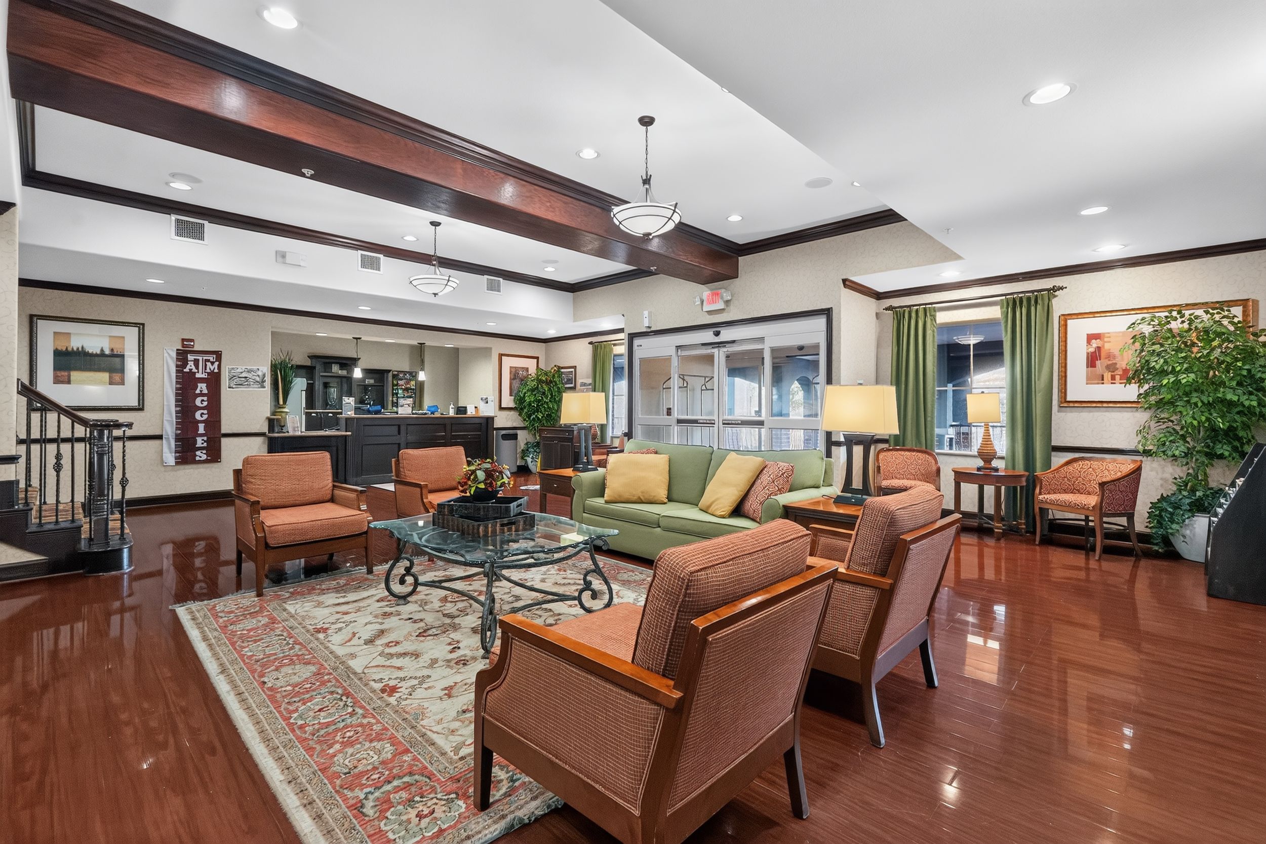 Elegant hotel lobby with hardwood floors, plush seating, oriental rug, and warm lighting in a spacious lounge area.