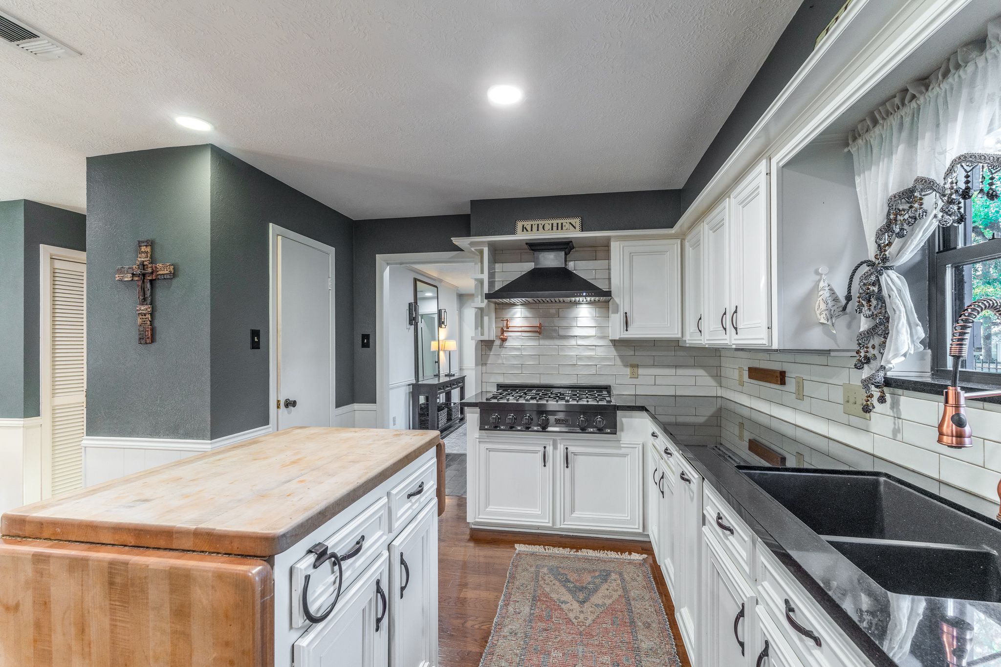 Modern kitchen remodel features white cabinets, butcher block countertops, and stainless steel appliances with recessed lighting.