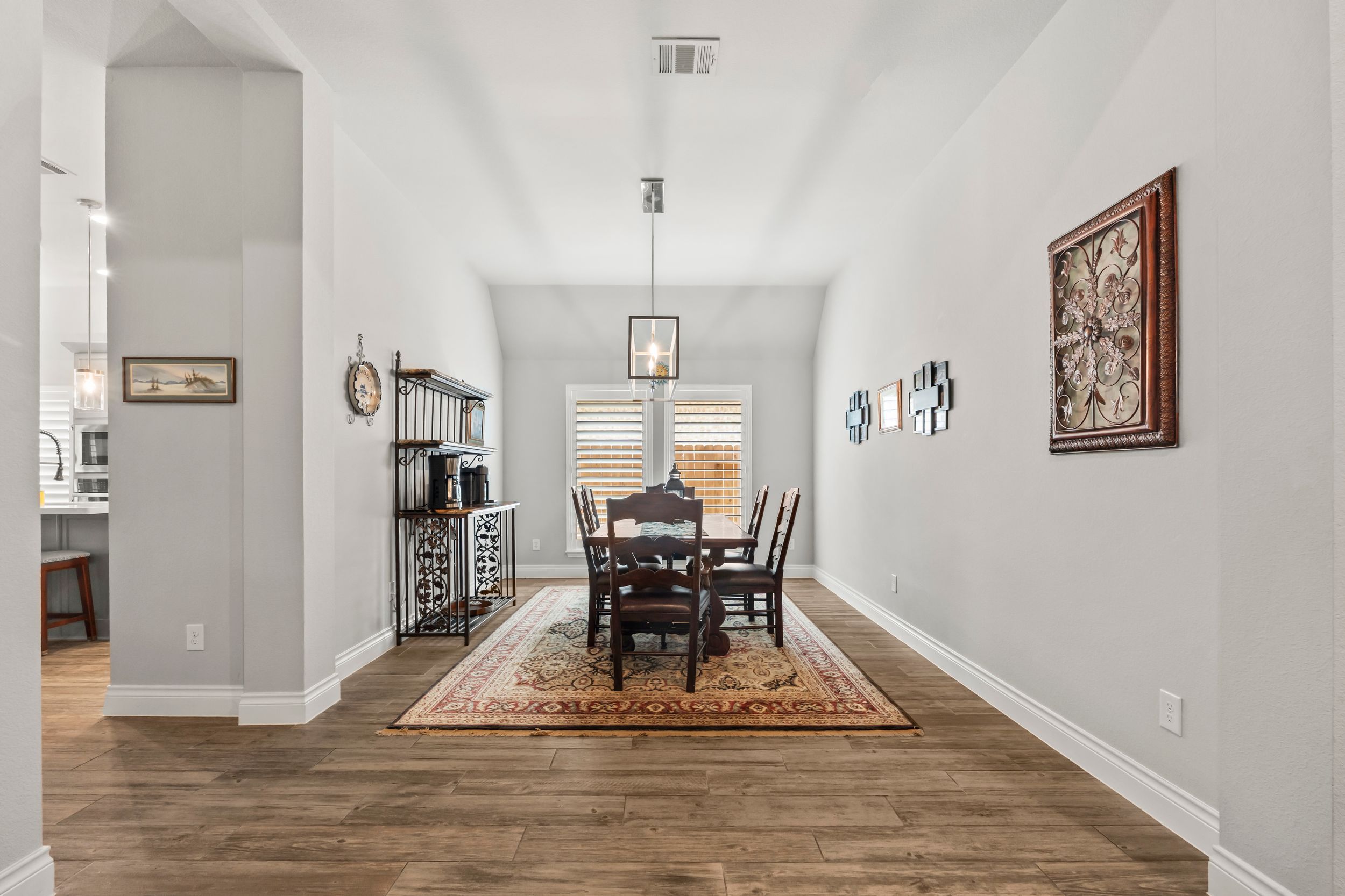 Elegant dining room with hardwood floors, a chandelier, dark wood table set, and neutral walls with decorative accents.