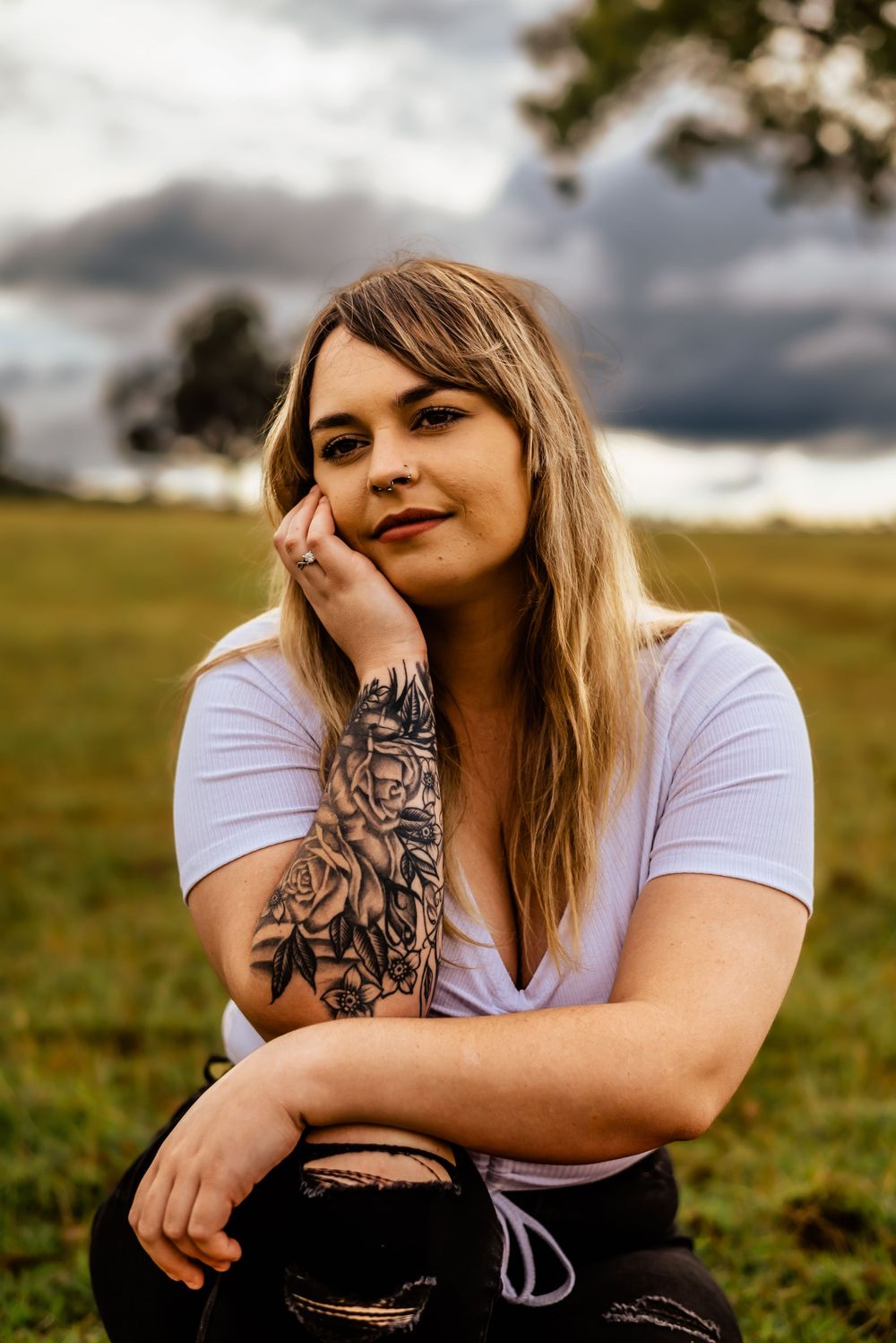 Casual portrait in field showcases intricate floral arm tattoo design.