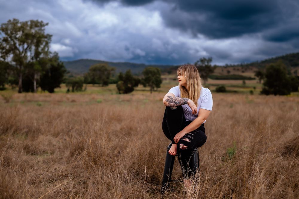 Moody landscape photograph with figure standing among tall grass.
