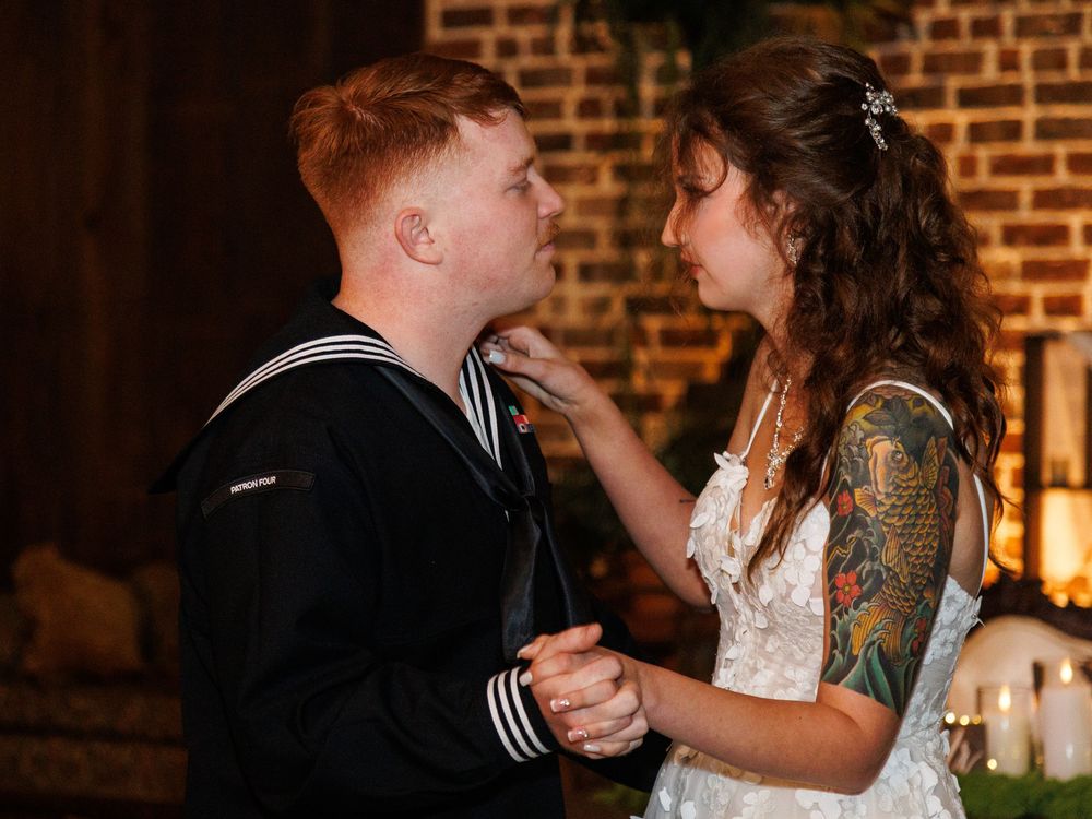 Navy sailor groom and tattooed bride share a romantic first dance at their wedding reception.