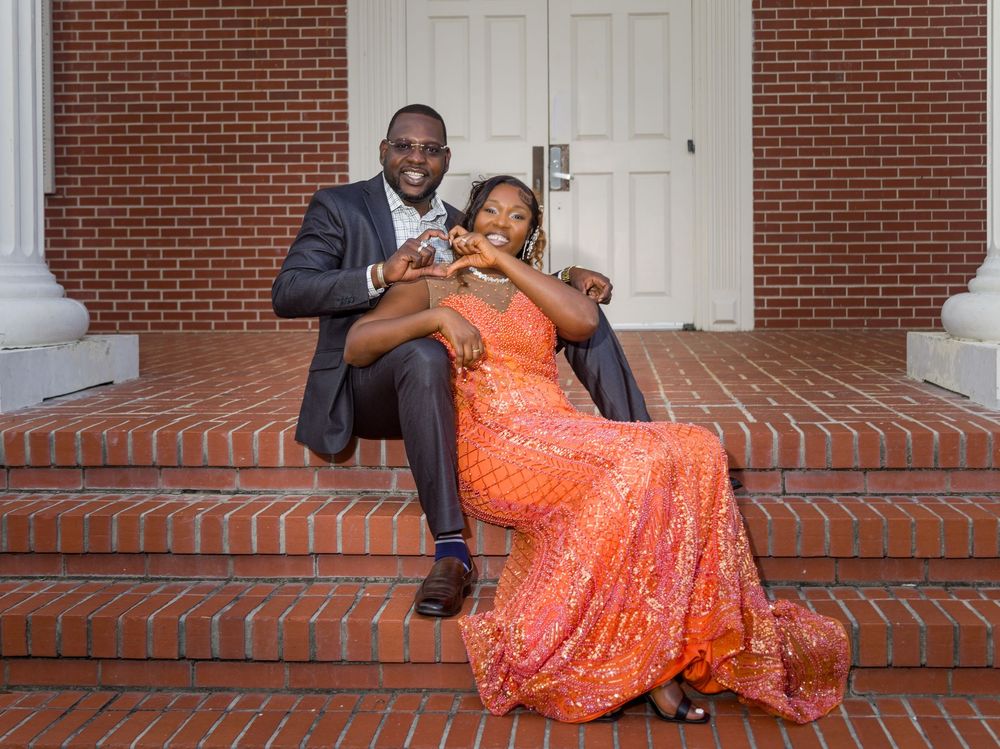 A couple in formal attire shares romantic moments on brick steps outside a white door.