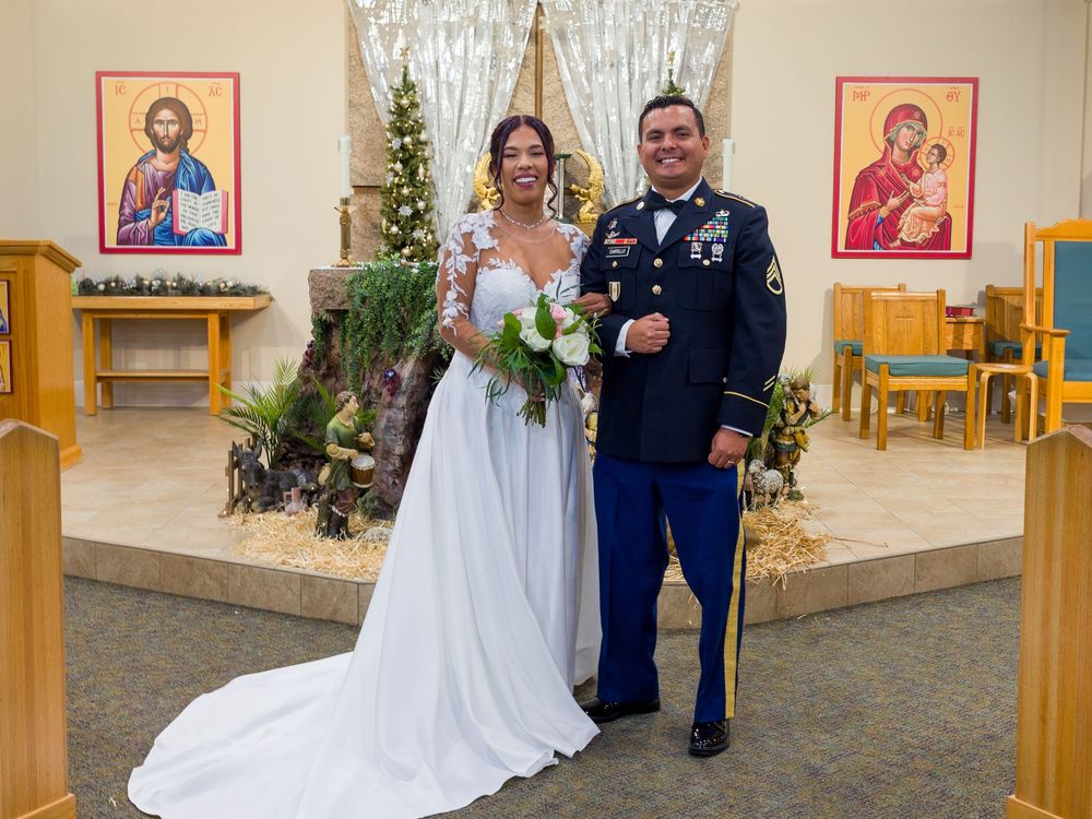 A couple shares a joyful moment during their wedding ceremony in a church decorated with Christmas trees and icons.