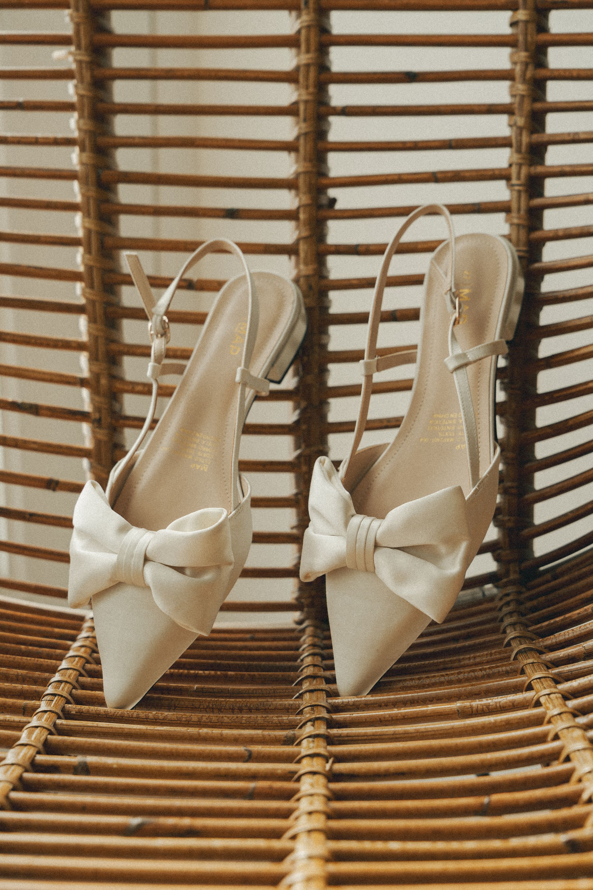 White bridal shoes displayed on wooden slat furniture creating an artistic wedding detail shot.