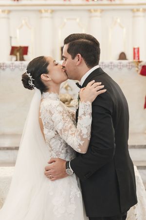 Romantic wedding couple sharing intimate kisses in an elegant indoor venue with classic decor.