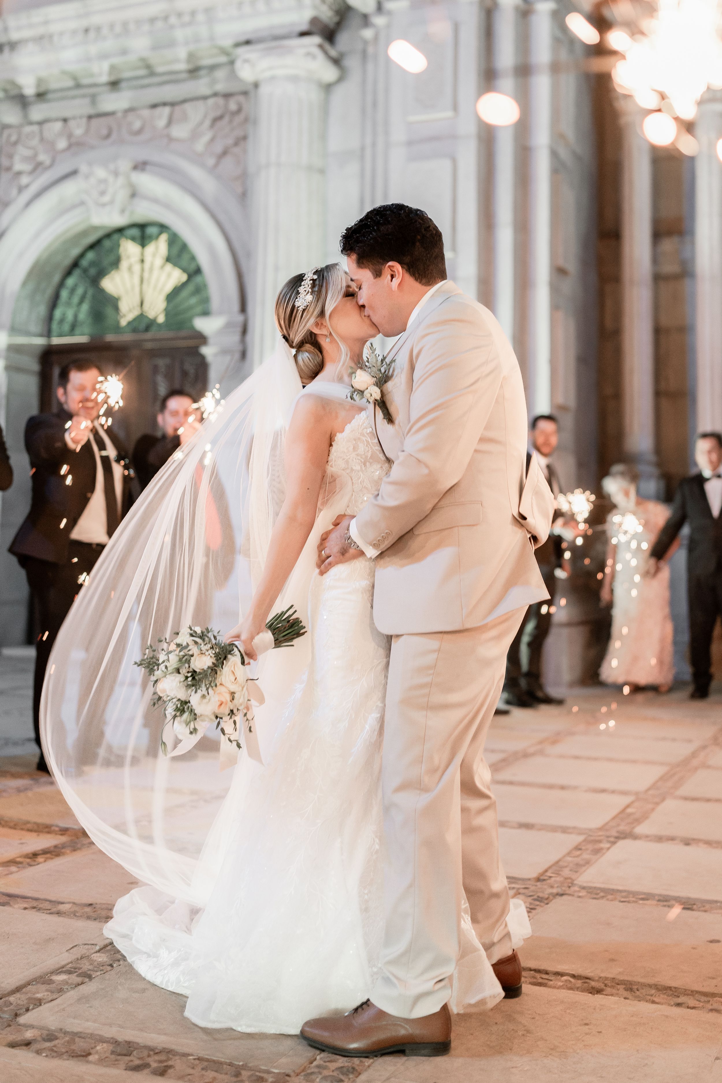 Wedding couple shares an intimate dance moment under ornate architecture and soft lighting.