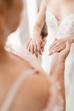 Close-up detail of hands adjusting a delicate white lace wedding dress.