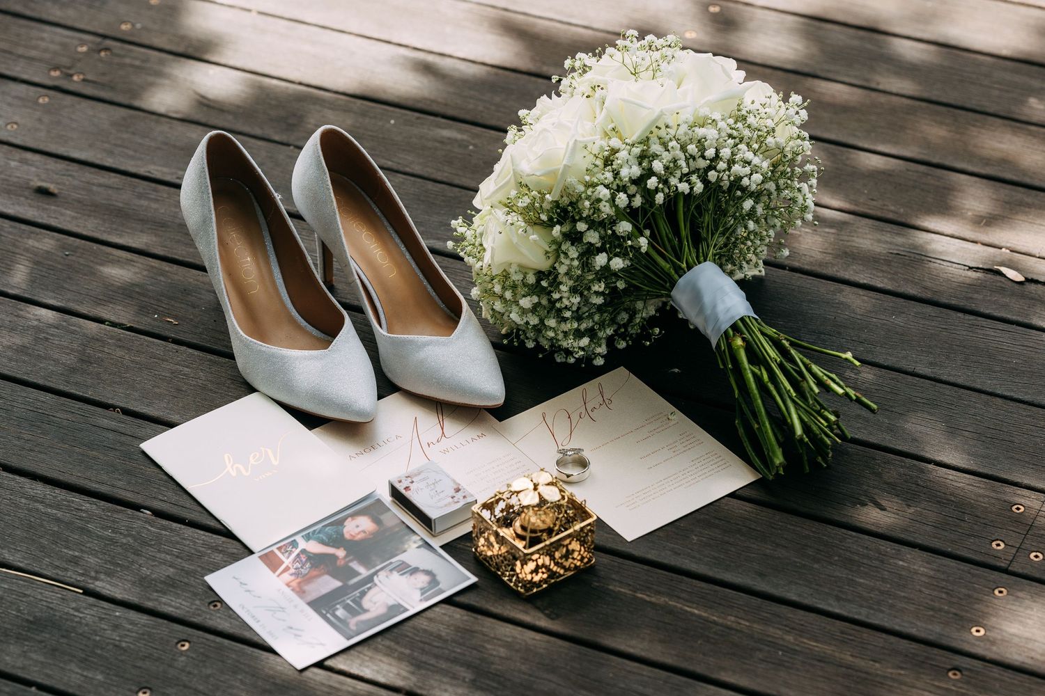 Wedding details with silver heels and baby's breath bouquet on wooden deck.