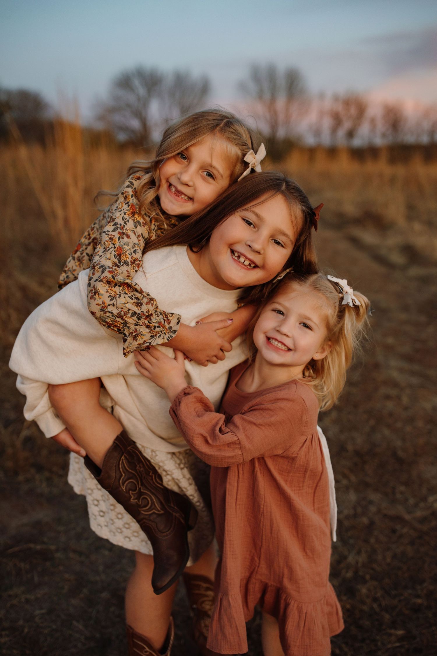 Two young children in autumn outfits hug and laugh together during a sunset outdoor photoshoot.