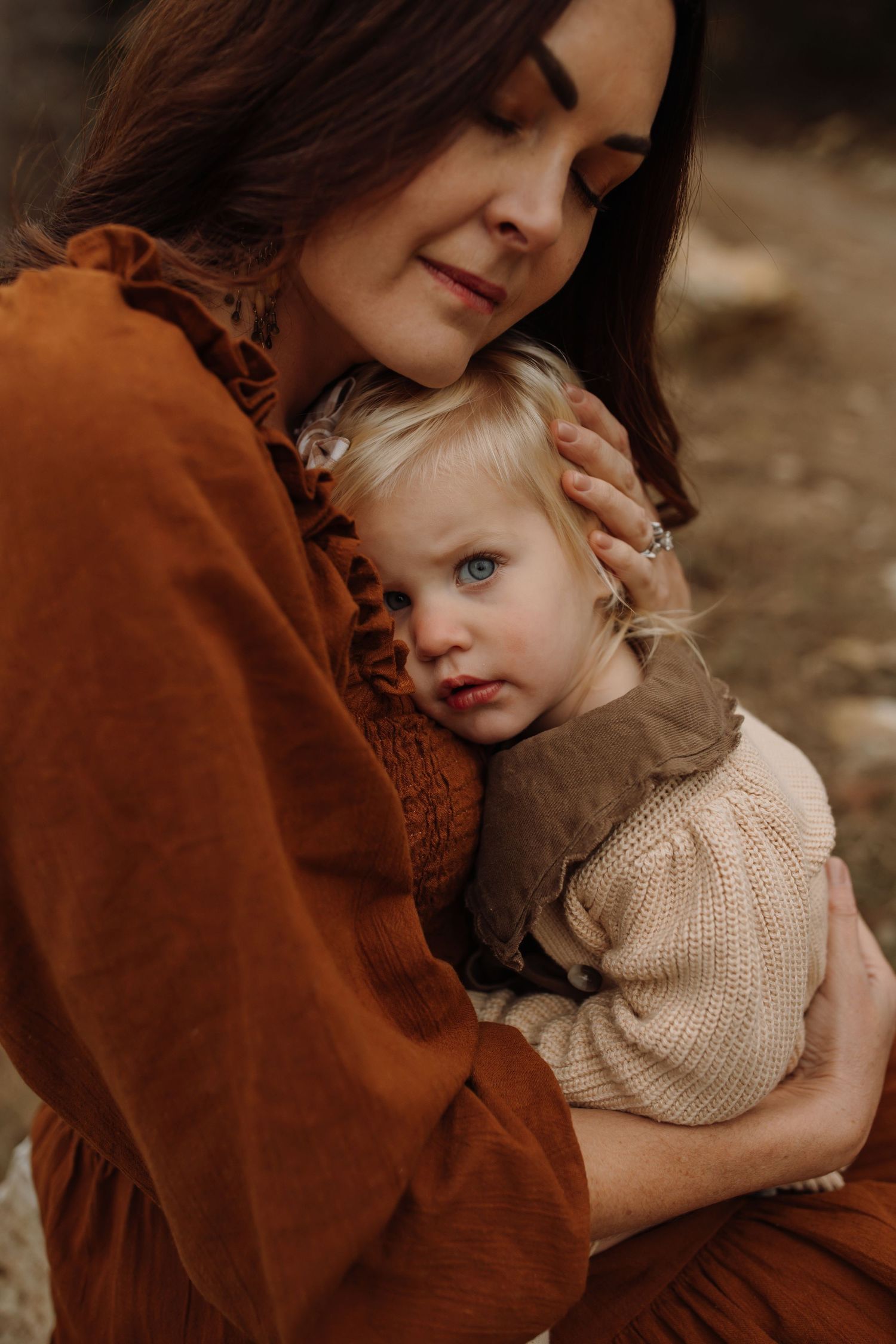 A tender embrace captured in warm autumn tones shows a parent and child sharing an intimate moment in matching beige knitwear.