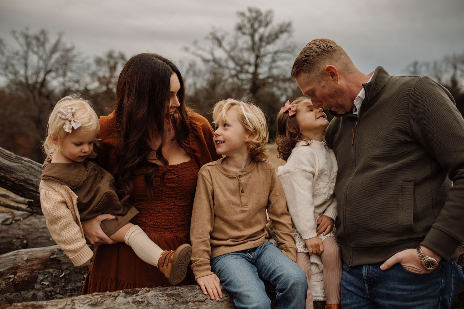 A cozy family photo session outdoors during autumn showing candid moments and warm earth-toned clothing.