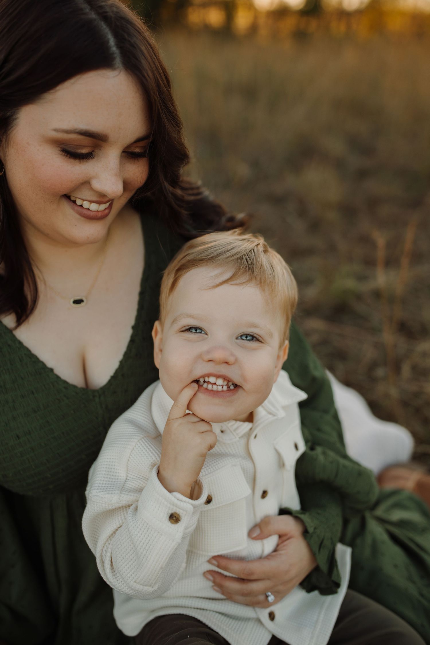 A tender moment shared between parent and child sitting together in a field during golden hour.