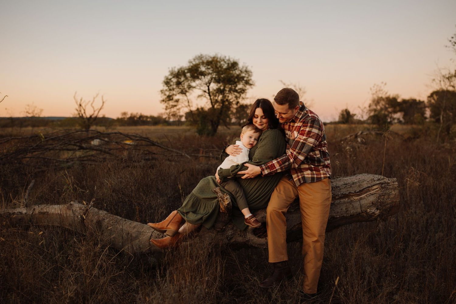Couple enjoying a romantic sunset moment on a rocky cliff overlooking a scenic landscape.