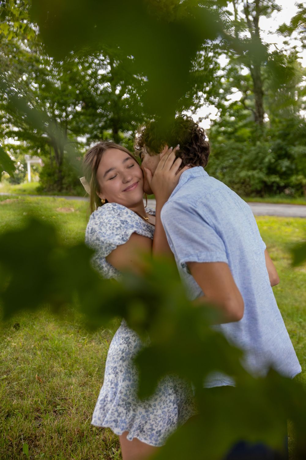 Romantic couple embracing in a garden setting with soft natural lighting and green foliage.