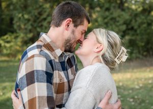 A romantic couple shares an intimate moment outdoors wearing casual fall clothing.