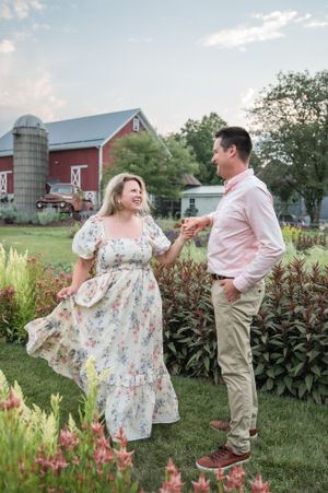 Romantic scene of a couple laughing together by a red barn and silo.