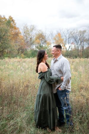 Couple shares intimate moment in tall autumn grass during outdoor photoshoot.