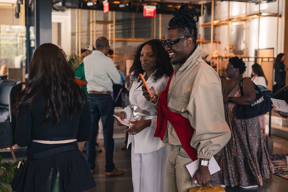 Diverse group of professionals networking at an indoor event, engaged in conversation in a modern venue.