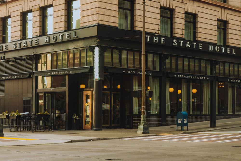 The State Hotel building stands on a downtown street corner with classic architecture and warm evening lighting.