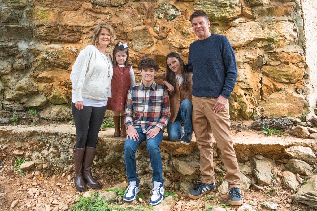 A group posing together against a rustic stone wall backdrop in casual attire.