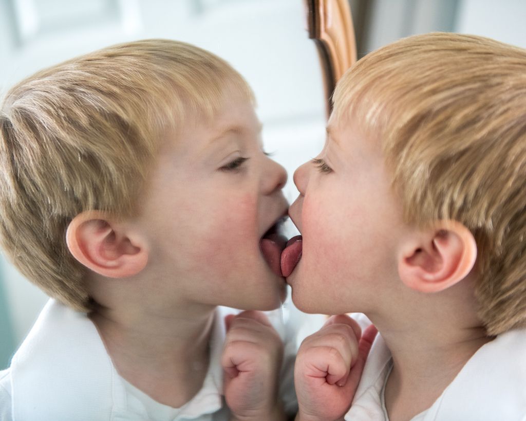 Two young siblings share a playful moment touching noses.