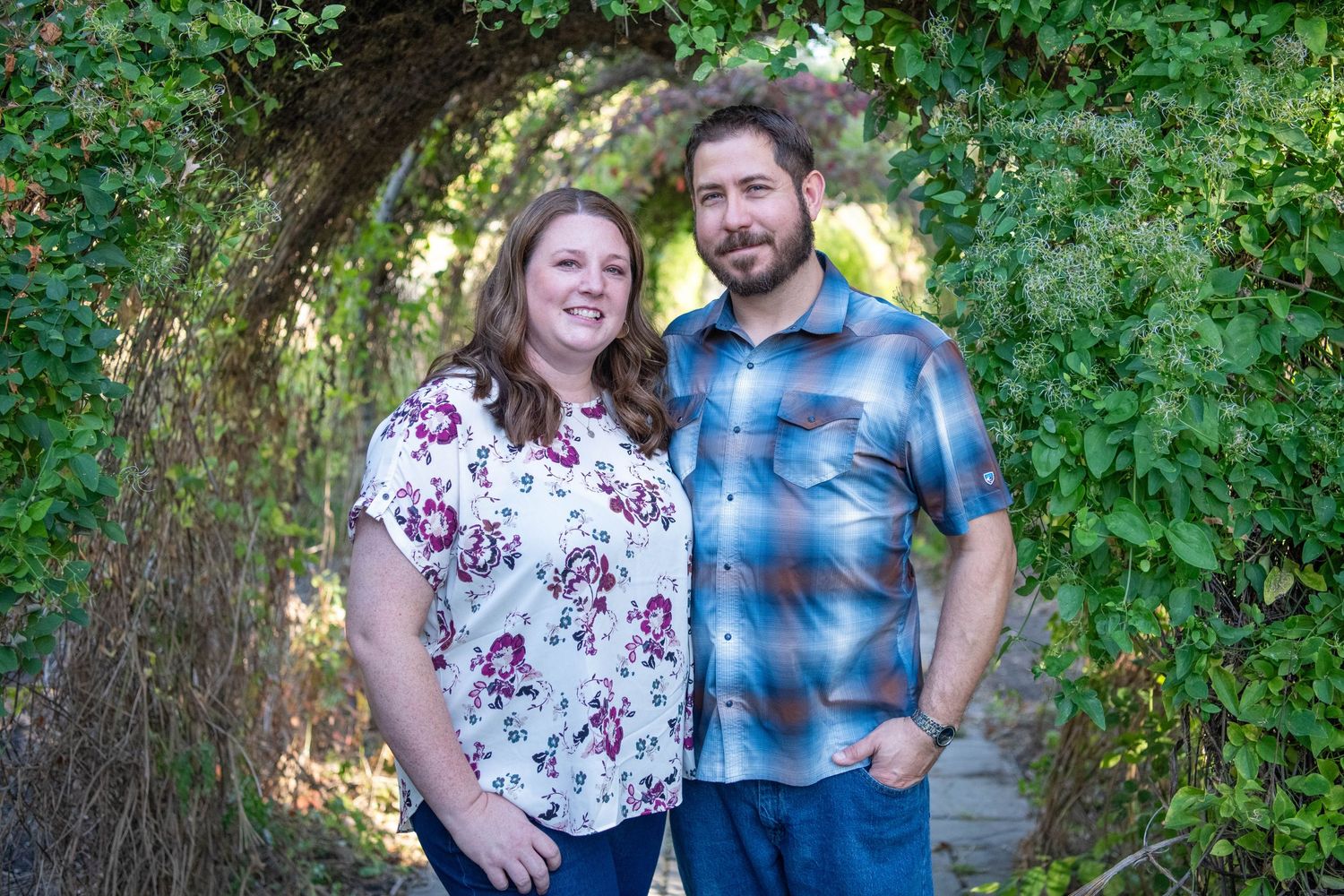 A couple shares a romantic moment together in a lush green garden setting during a photo session.