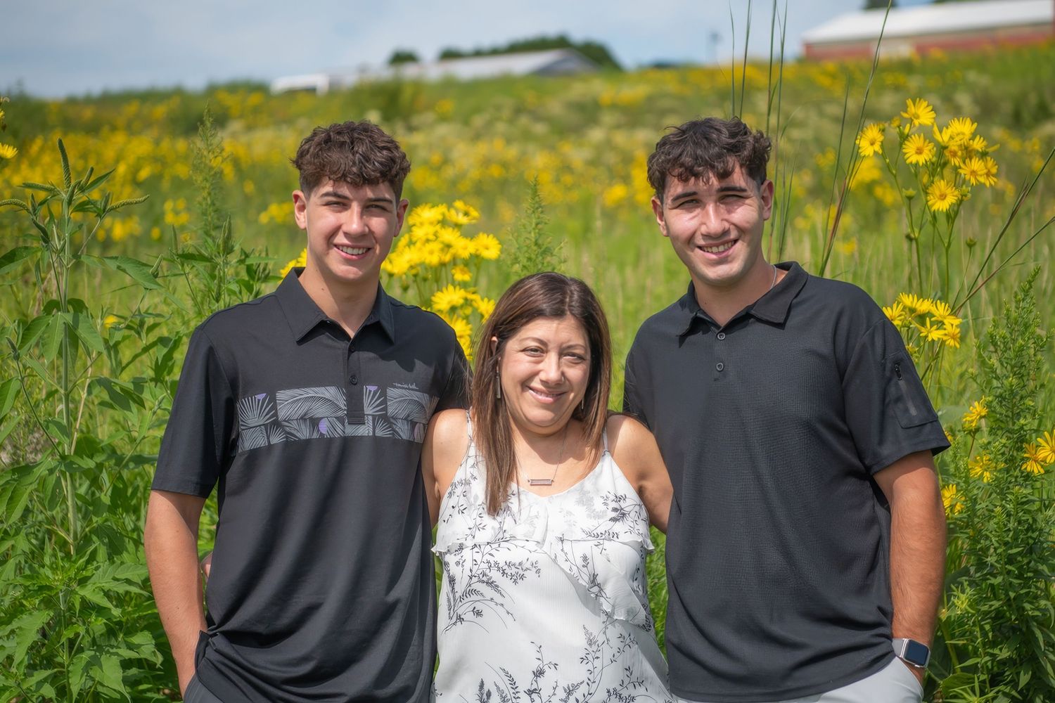 Family portrait in front of a scenic lake with blooming yellow wildflowers.