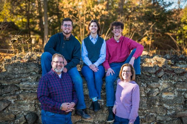 A group sits together on a stone wall during a golden sunset photoshoot in autumn.