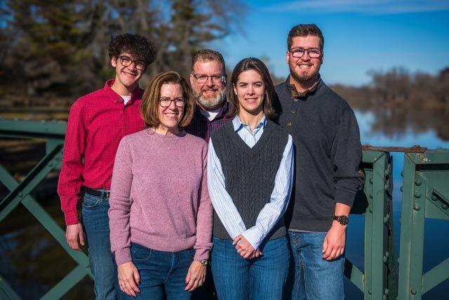 A series of outdoor family portraits taken on a wooden deck against a scenic lake backdrop on a sunny day.
