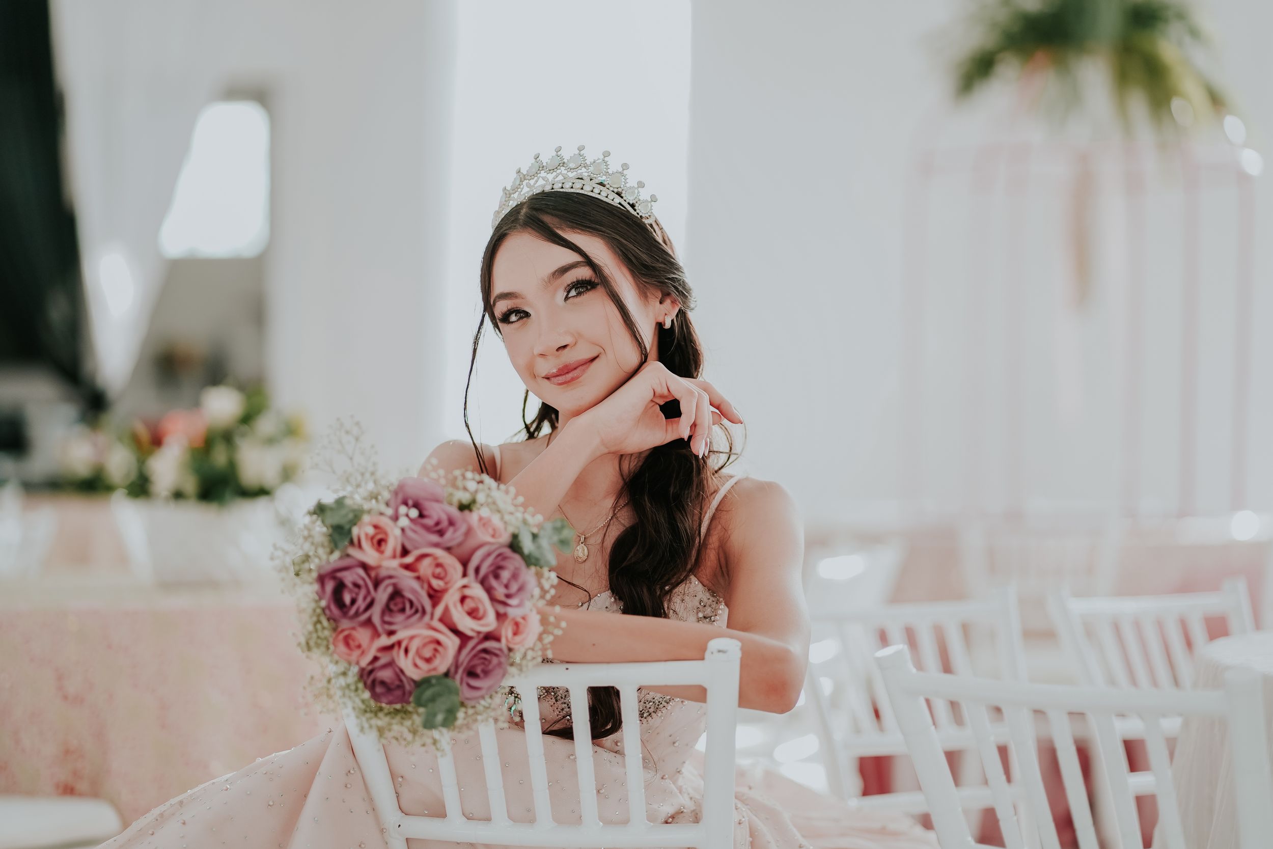 Elegant wedding reception table setting with soft pink floral centerpieces and white decor in a bright airy venue.