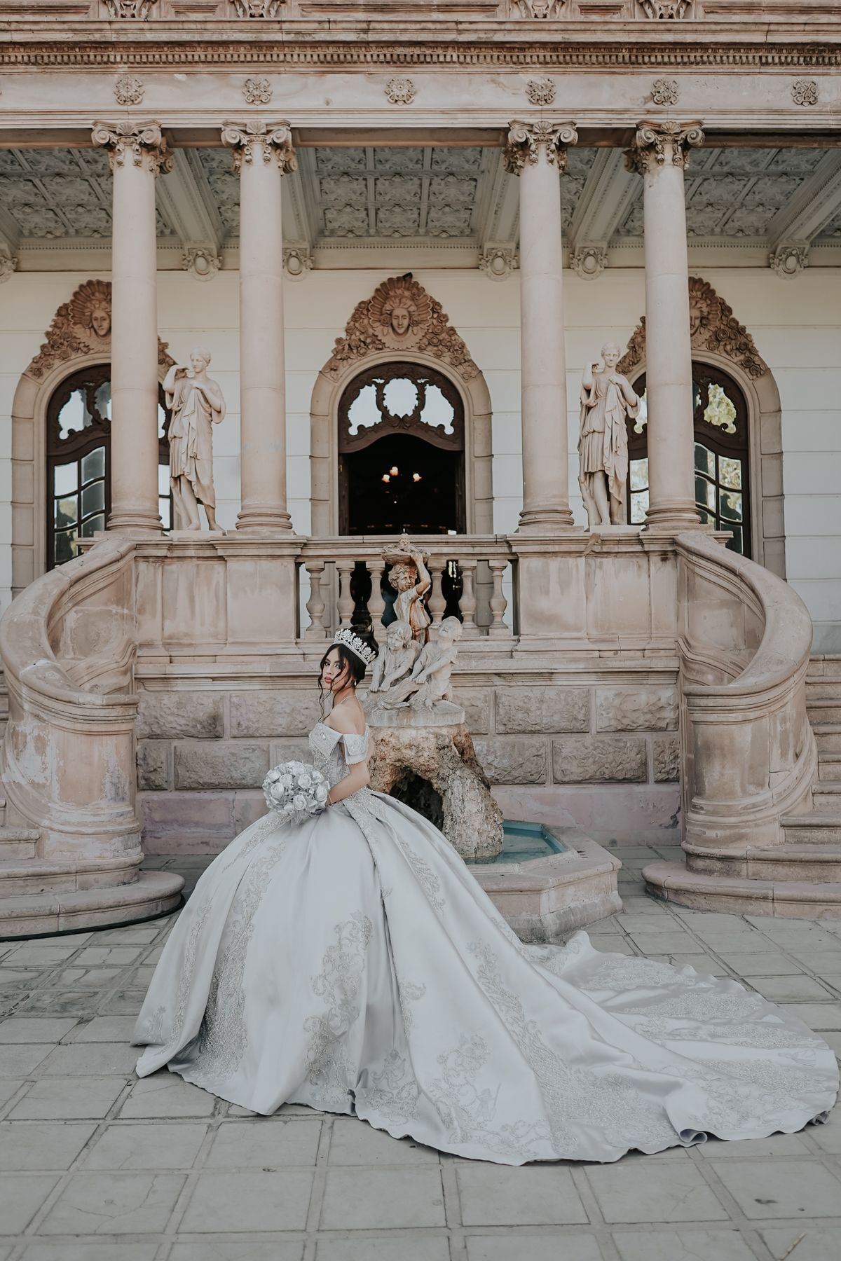 A classic bridal portrait taken on ornate marble steps with detailed architectural elements.
